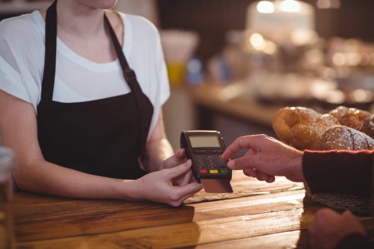 Customer-entering-pin-number-into-machine-at-counter-in-cafe